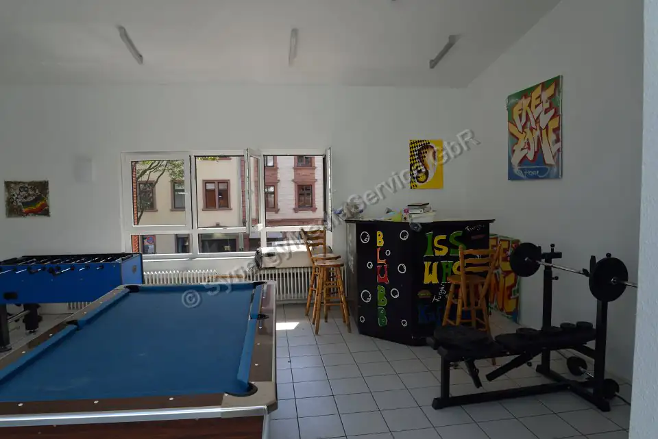 Locale ricreativo con biliardo e attrezzature da palestra Locale ricreativo luminoso con biliardo, calcetto, attrezzature da palestra e bar, grande vetrata.